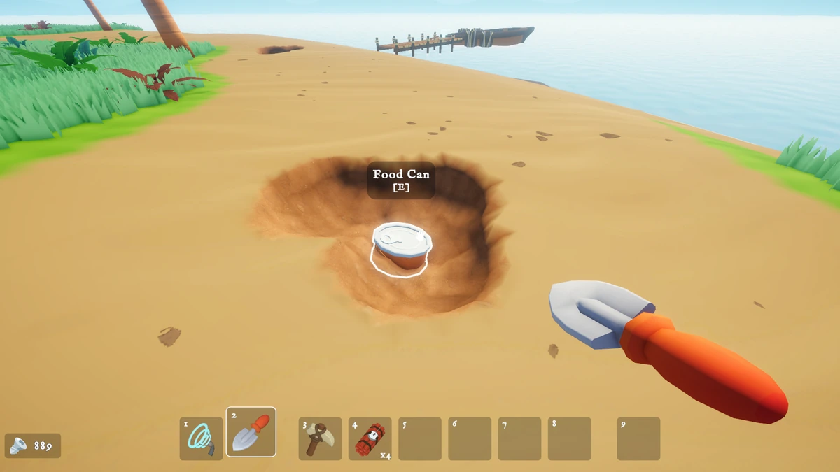 A shovel uncovering a buried food can in the sand